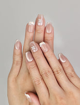 Hand wearing Naillover Whisper Beige handmade press on nails with sheer-to-nude gradient and silver gemstone accent.